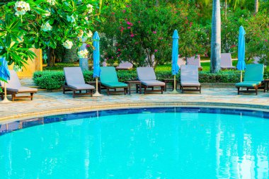 Hindistan cevizi palmiyeli havuz etrafında sandalye ve şemsiye - tatiller ve tatil kavramı