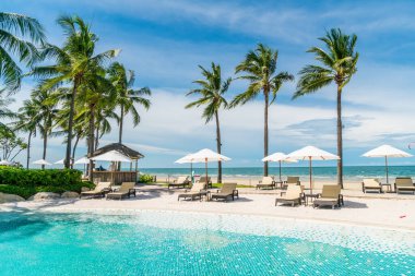 Plaj geçmişine sahip otel havuzunda yüzme havuzu etrafında plaj sandalyesi - tatil ve tatil kavramı