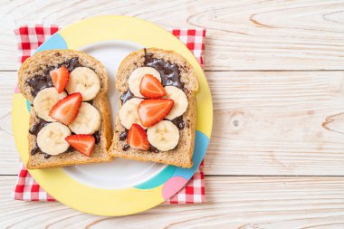 Kahvaltıda taze muz, çilek ve çikolatalı tam buğday ekmeği.