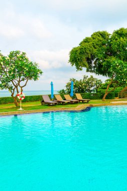 Sandalye havuzu ve şemsiyeyle okyanus arka planında yüzme havuzu