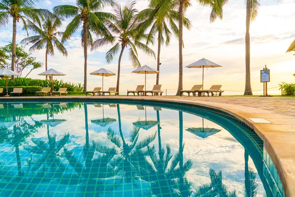 レジャー旅行や休暇のためのリゾートホテルのプールの周りの傘と椅子日没や日の出時に必要な海のビーチ — ストック写真