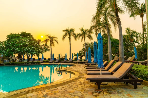Gün batımında yüzme havuzunda şemsiyeli plaj sandalyesi ya da bilardo yatağı