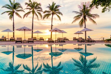 Şemsiye ve sandalye oteldeki yüzme havuzunda sabah gün doğumuyla birlikte - tatil ve tatil konsepti