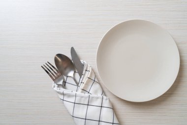 Ahşap zemin üzerinde bıçak, çatal ve kaşık olan boş tabak veya tabak
