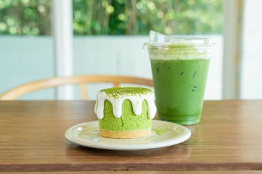 Kafe restoranındaki yeşil çay fincanlı kibrit yeşil çay peynirli kek.