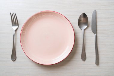 Ahşap zemin üzerinde bıçak, çatal ve kaşık olan boş tabak veya tabak