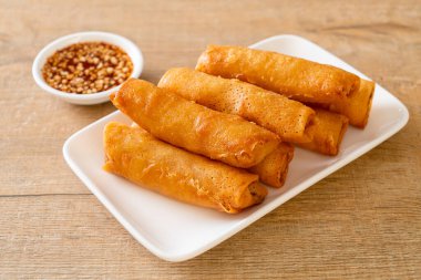 Kızarmış yumurta rulosu ve beyaz tabakta sos.