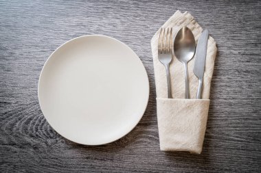 Ahşap zemin üzerinde bıçak, çatal ve kaşık olan boş tabak veya tabak