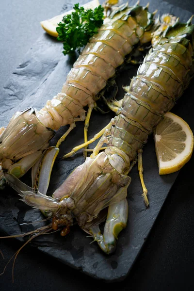 fresh mantis shrimp with lemon on black board