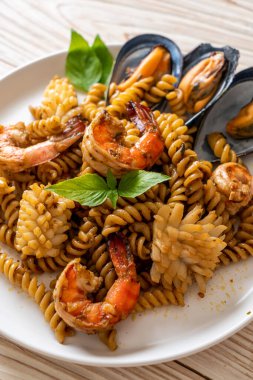 Deniz ürünleri ve fesleğen soslu kızarmış spiral makarna. Füzyon yemek tarzı.