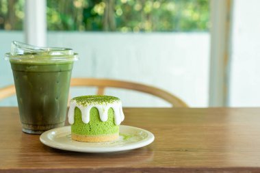 Kafe restoranındaki yeşil çay fincanlı kibrit yeşil çay peynirli kek.