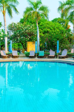 Hindistan cevizi palmiyeli havuz etrafında sandalye ve şemsiye - tatiller ve tatil kavramı