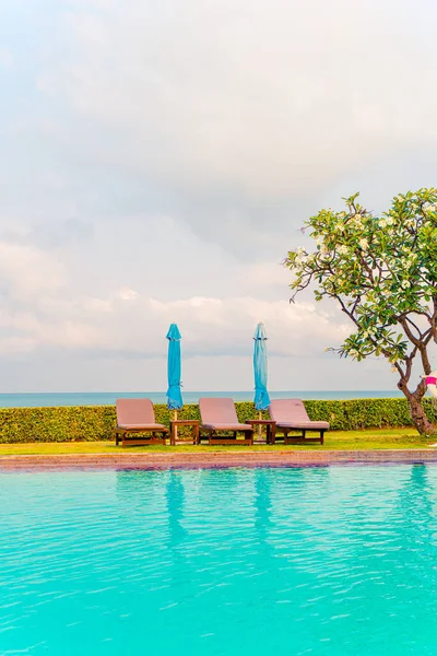 Sandalye havuzu ve şemsiyeyle okyanus arka planında yüzme havuzu