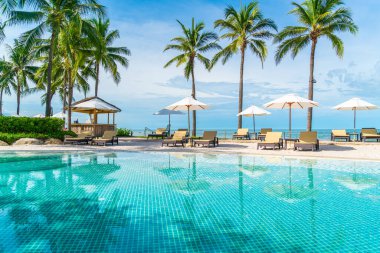 Güzel tropikal plaj ve deniz şemsiyesi ve sandalyesi otel tatil ve tatil için yüzme havuzunda.