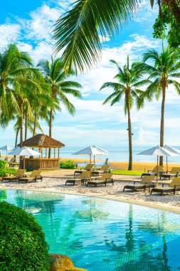 Otelde açık havuzda güzel bir şemsiye ve sandalye ve gün batımında hindistan cevizi palmiyesi ağacı olan bir tatil ve tatil konsepti.