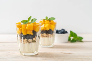 Ev yapımı taze mango ve yoğurt ve granola ile taze yaban mersini. Sağlıklı yemek tarzı.