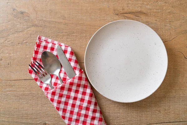 叉子和勺子在木制瓷砖底座上的空盘子或盘子 — 图库照片