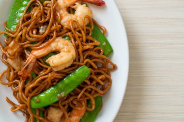 Kızarmış yakisoba eriştesi, yeşil bezelye ve karides, Asya usulü.