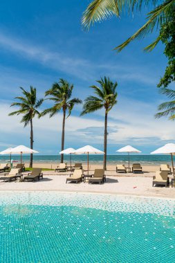 Plaj geçmişine sahip otel havuzunda yüzme havuzu etrafında plaj sandalyesi - tatil ve tatil kavramı