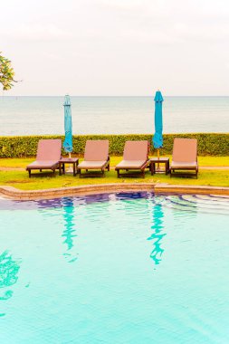 Sandalye havuzu ya da yüzme havuzu etrafında şemsiye olan yatak havuzu