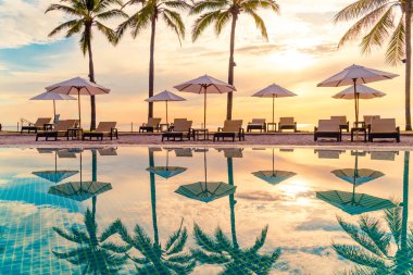 Şemsiye ve sandalye tatil ve tatil için dinlenme yeri otelinde yüzme havuzunda günbatımında veya gün doğumunda okyanus kıyısında