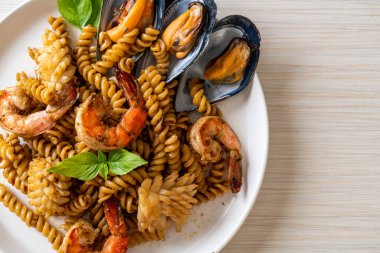 Deniz ürünleri ve fesleğen soslu kızarmış spiral makarna. Füzyon yemek tarzı.