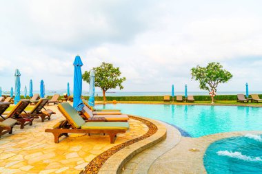 Tayland 'da Pattaya' da deniz plajı geçmişi olan havuz etrafında havuz ve şemsiye.