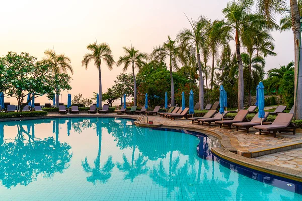 Gün batımında yüzme havuzunda şemsiyeli plaj sandalyesi ya da bilardo yatağı