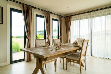 Perdesi ve penceresi olan bir odada ahşap yemek masası.