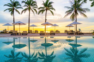 Şemsiye ve sandalye oteldeki yüzme havuzunda sabah gün doğumuyla birlikte - tatil ve tatil konsepti