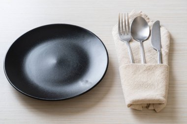 Ahşap zemin üzerinde bıçak, çatal ve kaşık olan boş tabak veya tabak