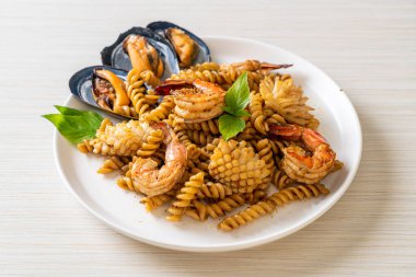 Deniz ürünleri ve fesleğen soslu kızarmış spiral makarna. Füzyon yemek tarzı.