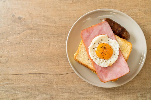 homemade bread toasted cheese topped ham and fried egg with pork sausage for breakfast