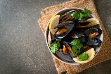 Limonlu bir kasede otlu taze midyeler.