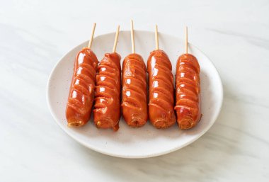 Beyaz tabakta kızarmış sosis şişi.