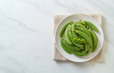 Taze yeşil bezelyeler beyaz tabakta