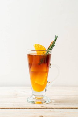 Bir bardak buzlu americano sade kahve ve ahşap arka planda biberiye ve tarçınla süslenmiş portakal ve limon suyu.