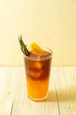 Bir bardak buzlu americano sade kahve ve biberiye ve tarçınla süslenmiş portakal ve limon suyu.