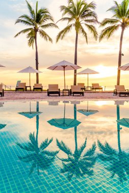 Şemsiye ve sandalye oteldeki yüzme havuzunda sabah gün doğumuyla birlikte - tatil ve tatil konsepti