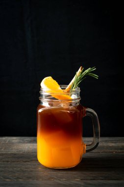 Bir bardak buzlu americano sade kahve ve biberiye ve tarçınla süslenmiş portakal ve limon suyu.