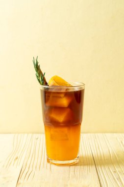 Bir bardak buzlu americano sade kahve ve biberiye ve tarçınla süslenmiş portakal ve limon suyu.