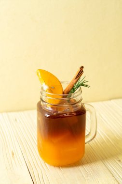 Bir bardak buzlu americano sade kahve ve biberiye ve tarçınla süslenmiş portakal ve limon suyu.