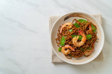 Kızarmış yakisoba eriştesi, yeşil bezelye ve karides, Asya usulü.