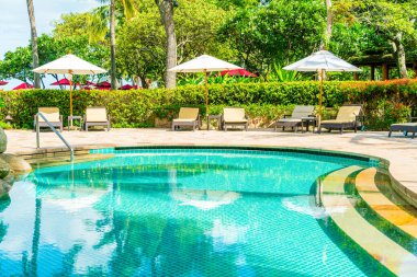 Güzel tropikal plaj ve deniz şemsiyesi ve sandalyesi otel tatil ve tatil için yüzme havuzunda.