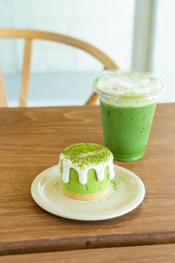 Kafe restoranındaki yeşil çay fincanlı kibrit yeşil çay peynirli kek.
