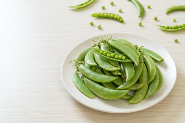 Taze yeşil bezelyeler beyaz tabakta