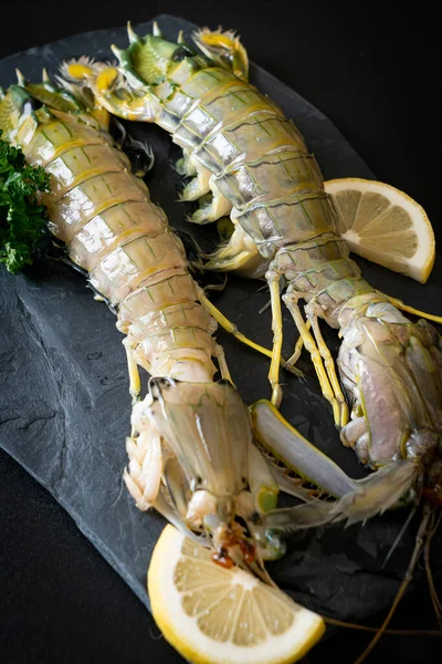 fresh mantis shrimp with lemon on black board