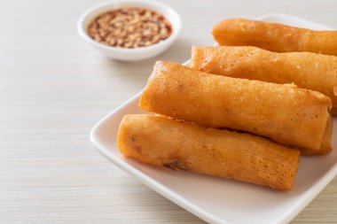 Kızarmış yumurta rulosu ve beyaz tabakta sos.