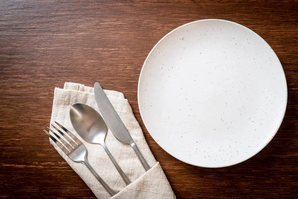 叉子和勺子在木制瓷砖底座上的空盘子或盘子 — 图库照片