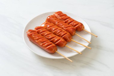 Beyaz tabakta kızarmış sosis şişi.